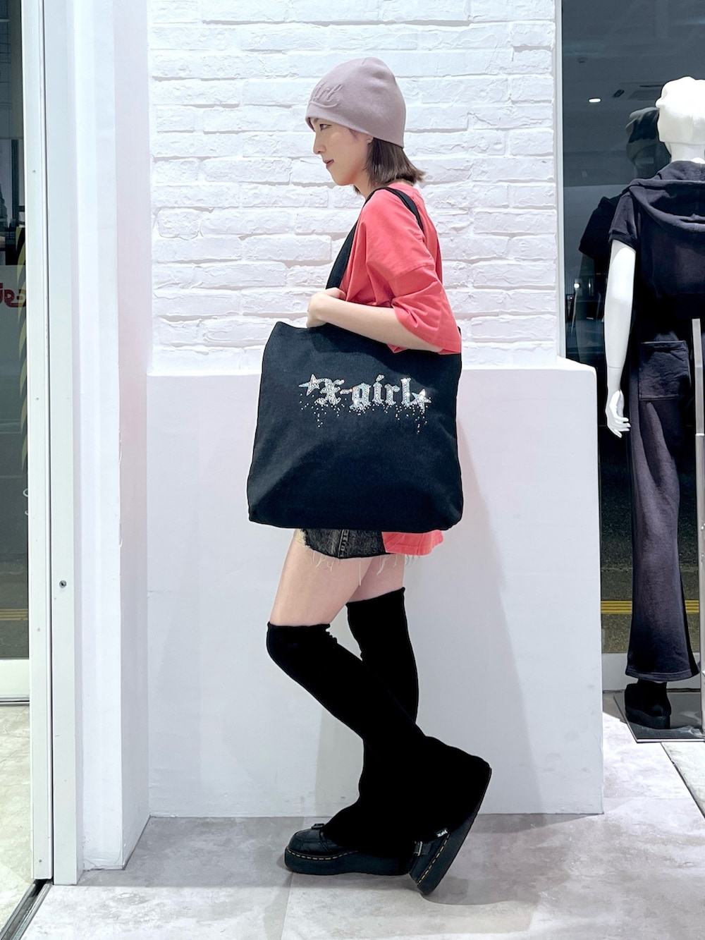 ブラック系のトートバッグ、ブラック系のデニムスカート、ピンク系のワンピースを着用したレディースの春コーディネートの2枚目の写真