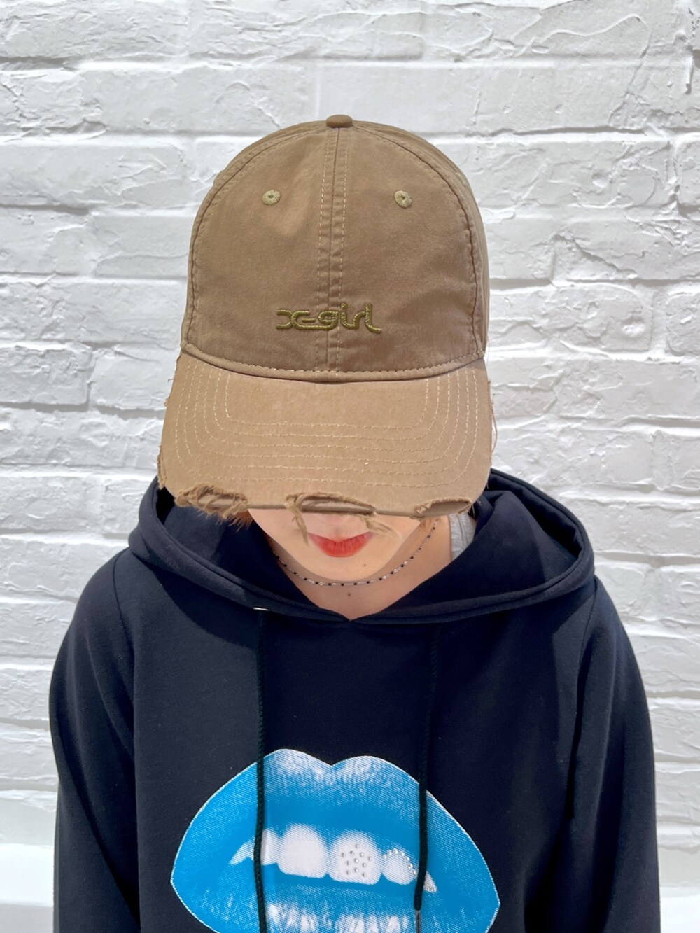 ブルー系のトートバッグ、ブラック系のワンピース、グリーン系のキャップを着用したレディースの春コーディネートの4枚目の写真