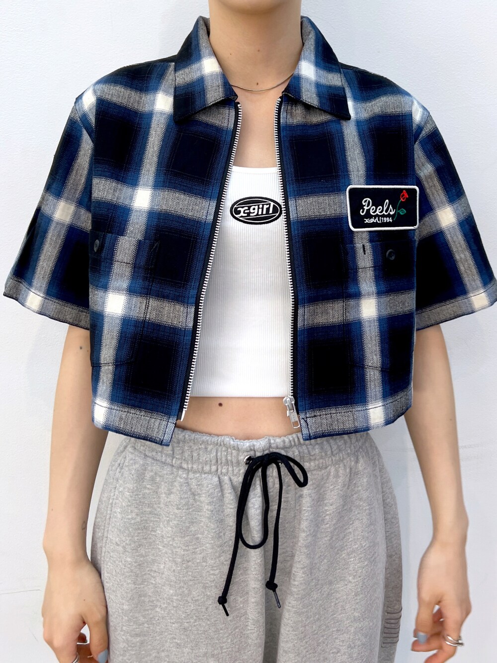 グレー系のスウェットパンツ、ブラック系のショルダーバッグ、ホワイト系のキャミソールを着用したレディースの夏コーディネートの3枚目の写真