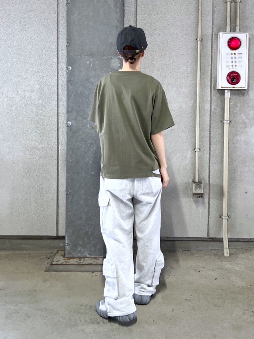 グリーン系のTシャツ/カットソー、グレー系のスウェットパンツ、ブラック系のキャップを着用したレディースの春コーディネートの2枚目の写真