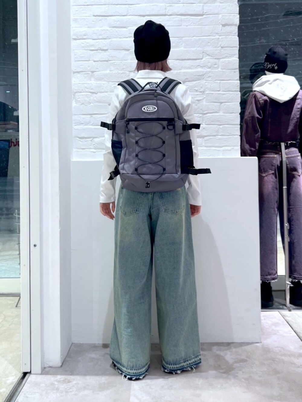 ブルー系のデニムパンツ、グレー系のバックパック/リュック、ホワイト系のTシャツ/カットソーを着用したレディースの冬コーディネートの2枚目の写真