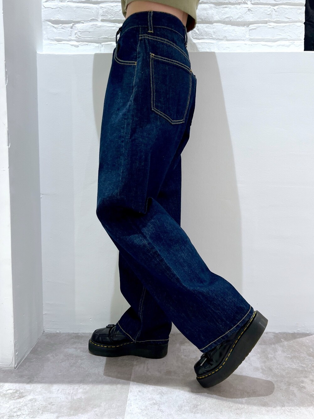 ブルー系のデニムパンツ、グリーン系のパーカー、ベージュ系のキャップを着用したレディースの春コーディネートの5枚目の写真