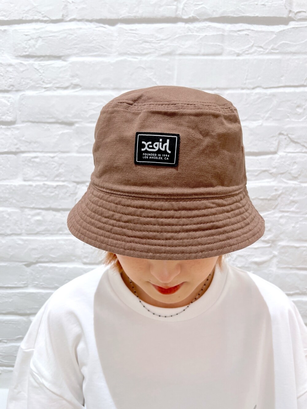 ブルー系のデニムパンツ、ホワイト系のTシャツ/カットソー、ベージュ系のハットを着用したレディースの春コーディネートの7枚目の写真