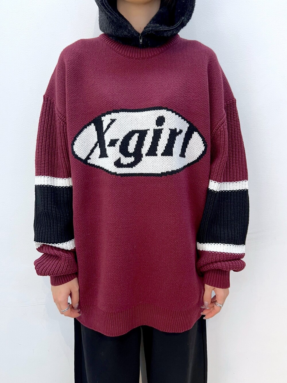 レッド系のニット/セーター、ブラック系のスウェットパンツ、ベージュ系のハンドバッグを着用したレディースの冬コーディネートの3枚目の写真