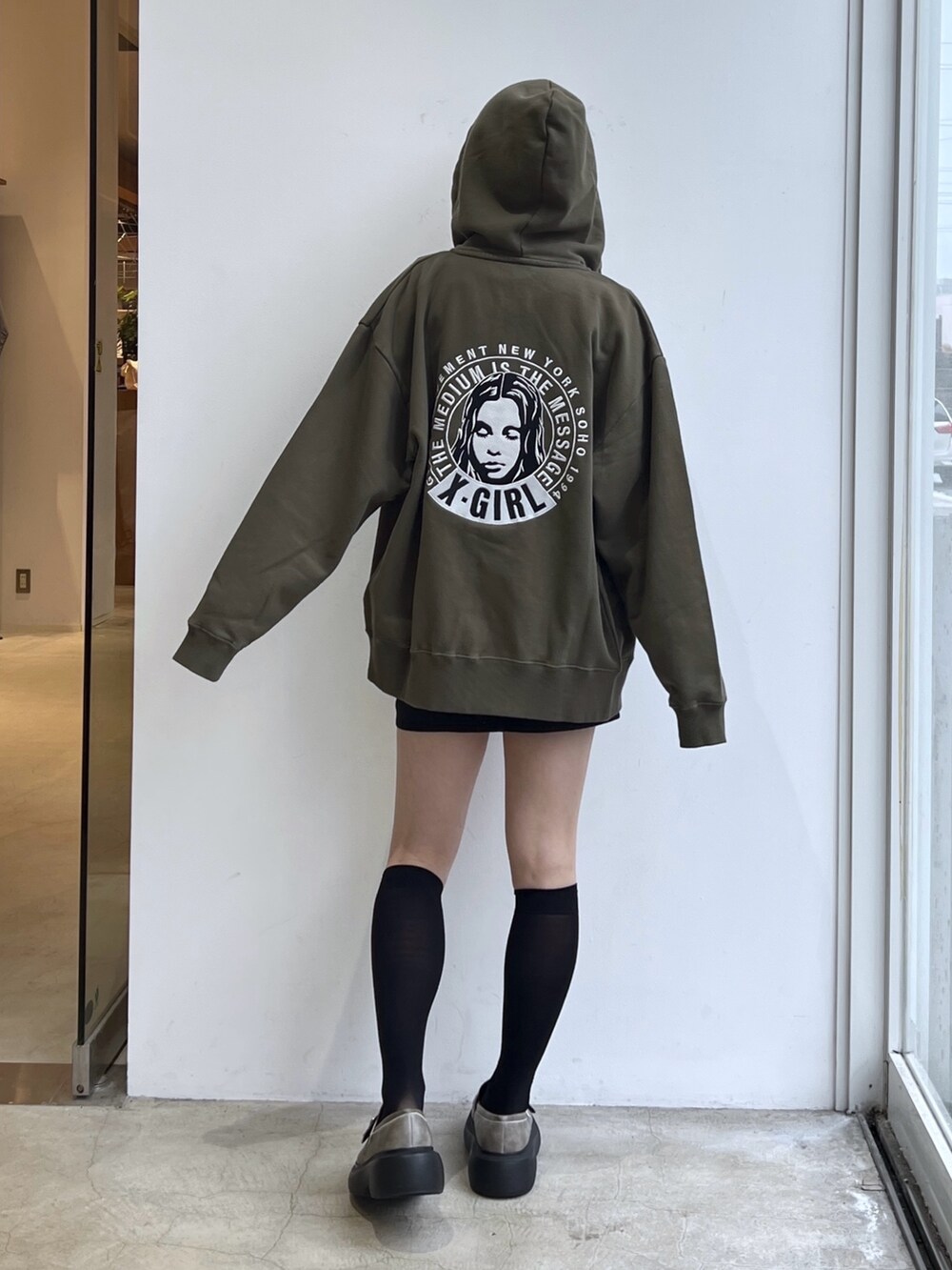 ブラック系のスカート、グリーン系のパーカー、ホワイト系のTシャツ/カットソーを着用したレディースの冬コーディネートの2枚目の写真