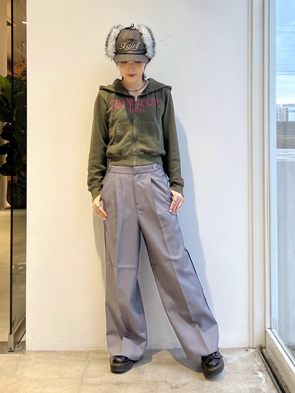 グレー系のスラックス、グリーン系のパーカー、ブラック系のキャップを着用したレディースの秋コーディネートの2枚目の写真