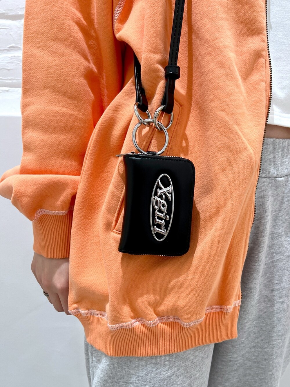 グレー系のスウェットパンツ、オレンジ系のスウェット、ホワイト系のパーカーを着用したレディースの春コーディネートの7枚目の写真