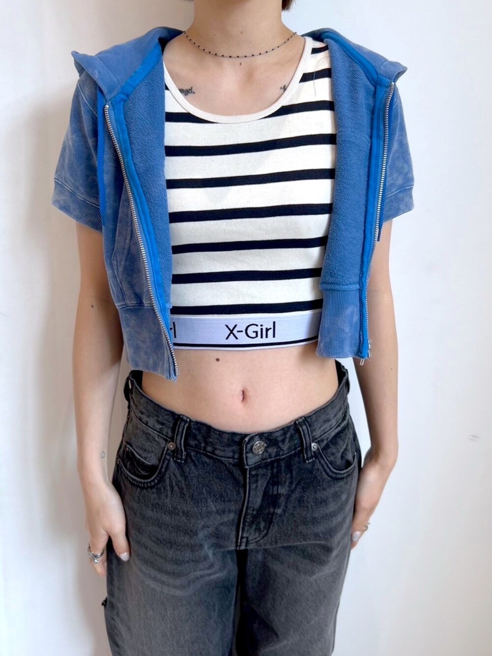 ブラック系のデニムパンツ、ブルー系のパーカー、その他のタンクトップを着用したレディースの春コーディネートの3枚目の写真