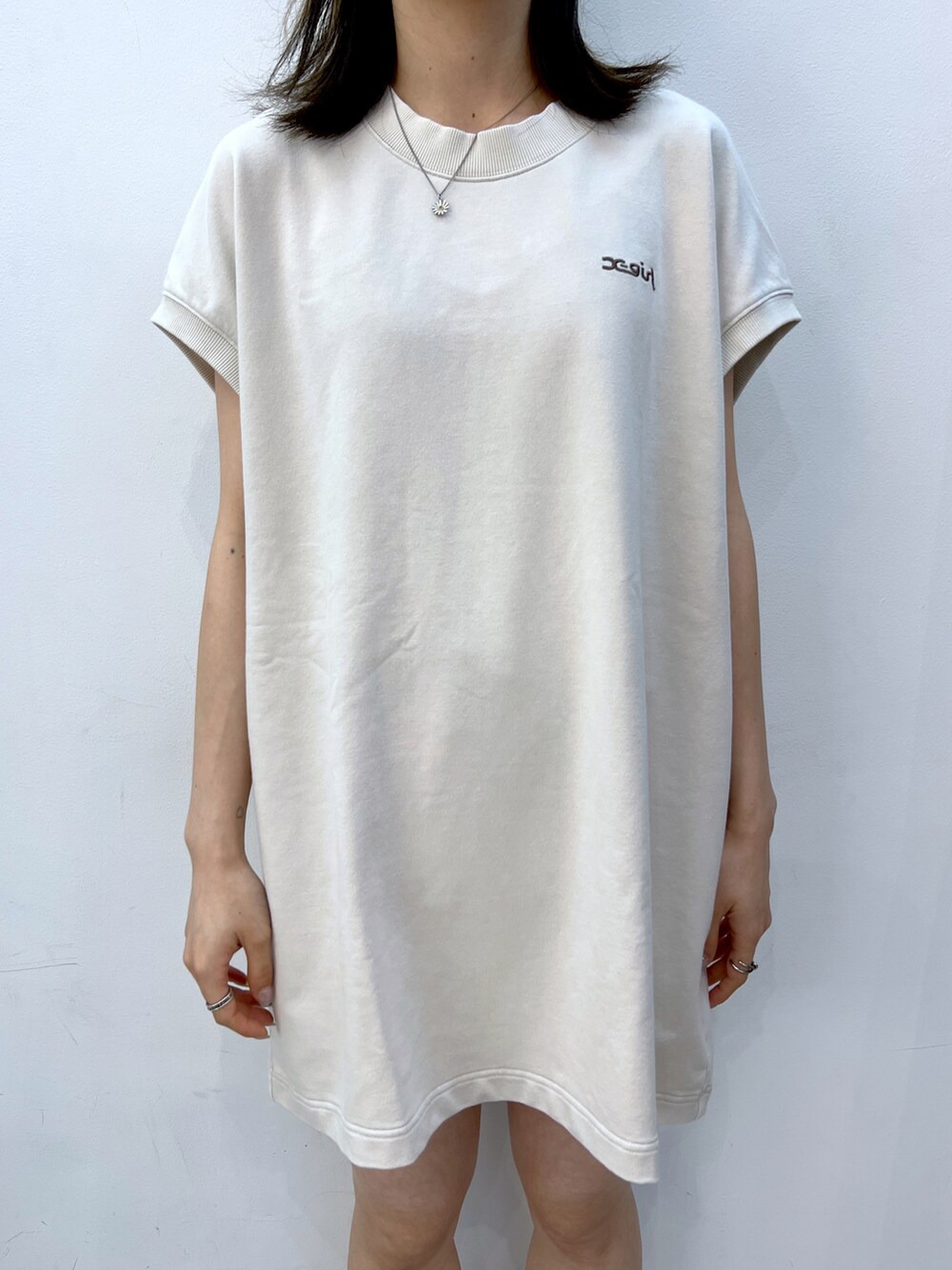 ホワイト系のワンピース、ブラック系のトートバッグ、グリーン系のキャップを着用したレディースの夏コーディネートの3枚目の写真