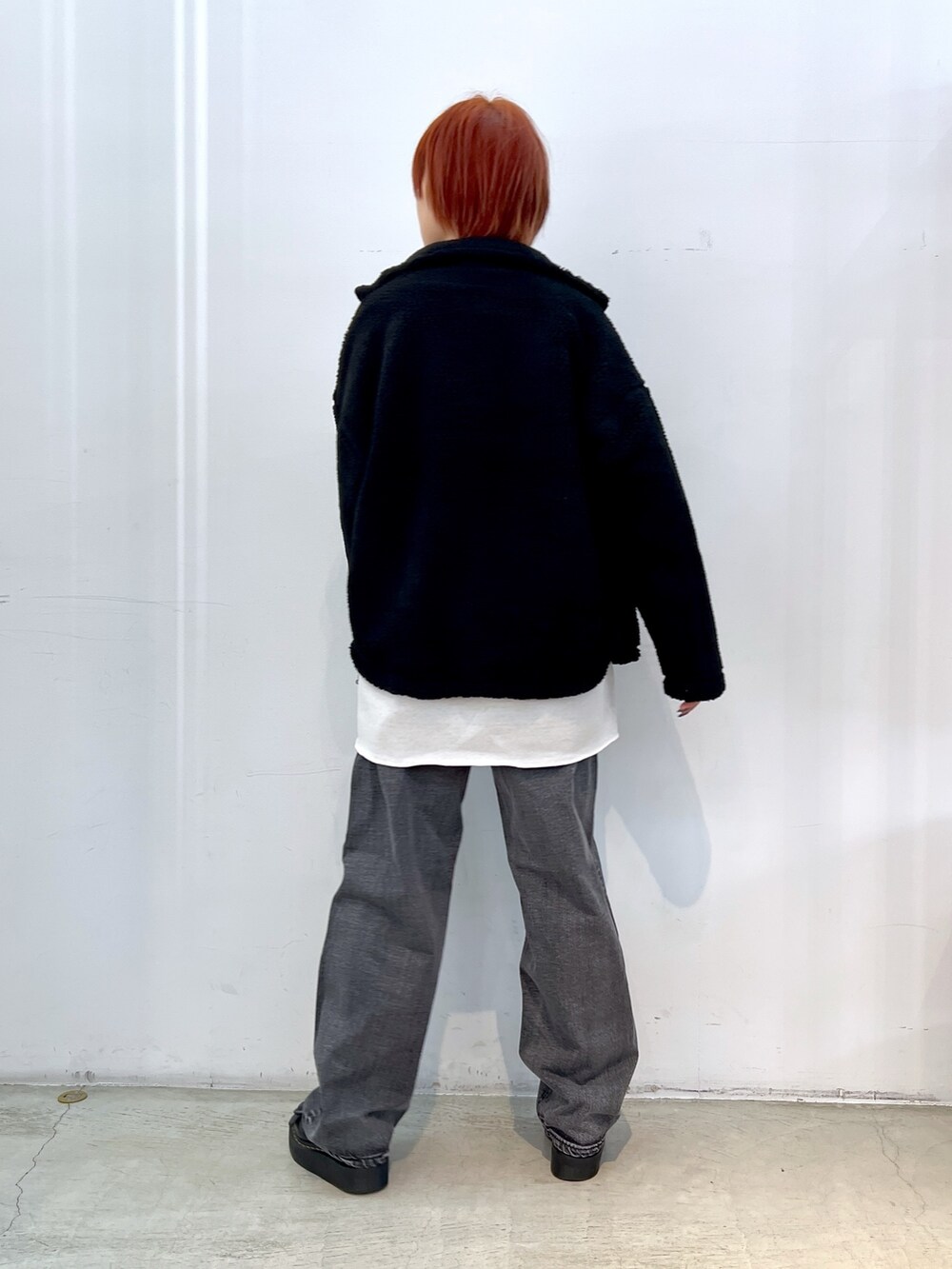 ブラック系のデニムパンツ、ホワイト系のニット/セーター、ブラック系のブルゾンを着用したレディースの冬コーディネートの2枚目の写真