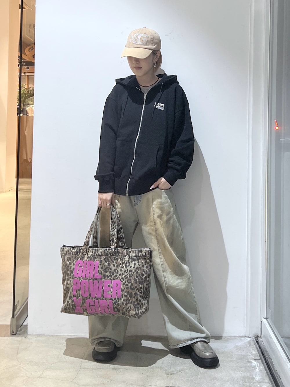 ベージュ系のトートバッグ、ブルー系のデニムパンツ、ブラック系のパーカーを着用したレディースの春コーディネートの2枚目の写真