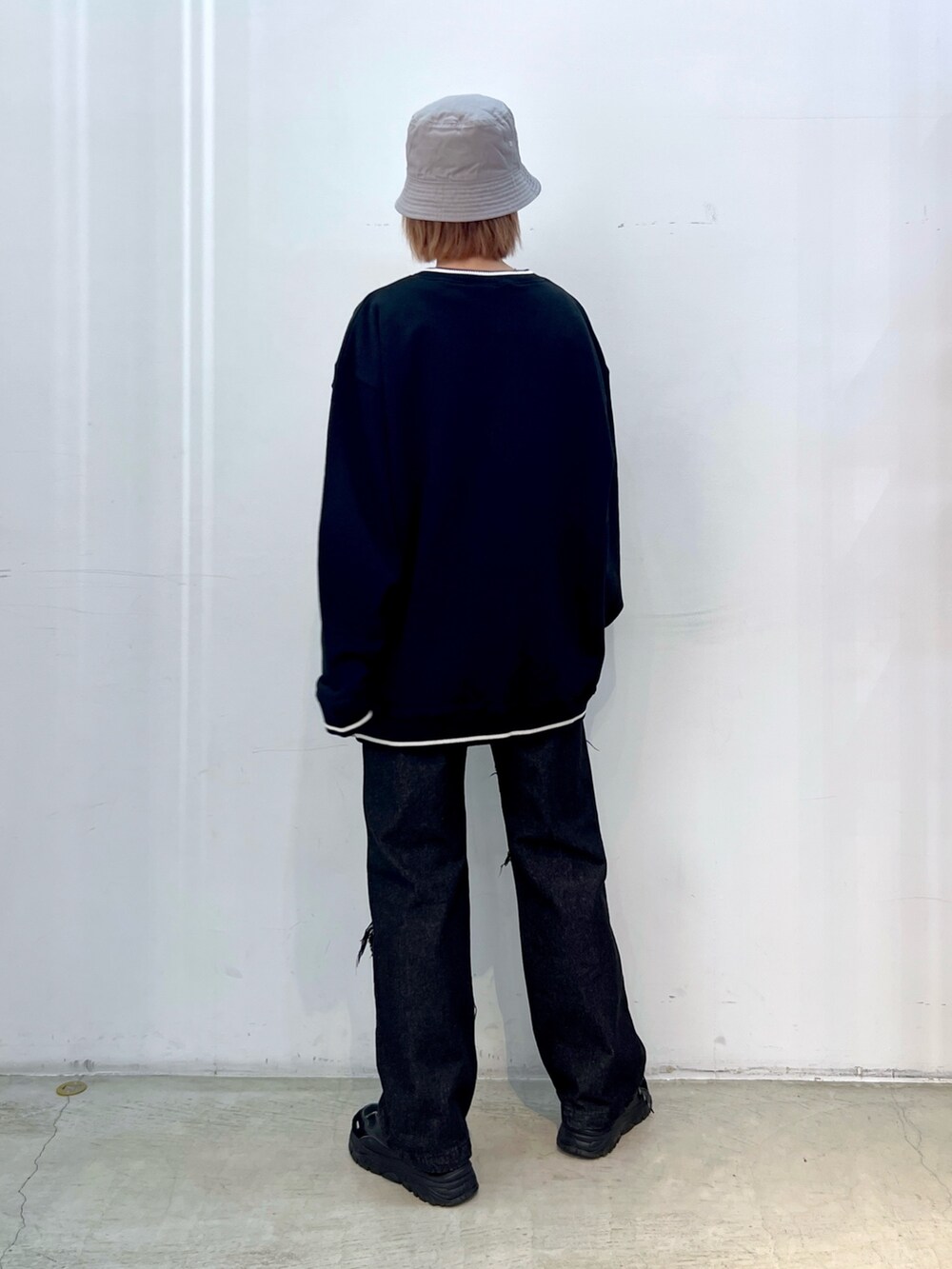 ブラック系のデニムパンツ、ブラック系のスウェット、ブルー系のハットを着用したレディースの冬コーディネートの2枚目の写真