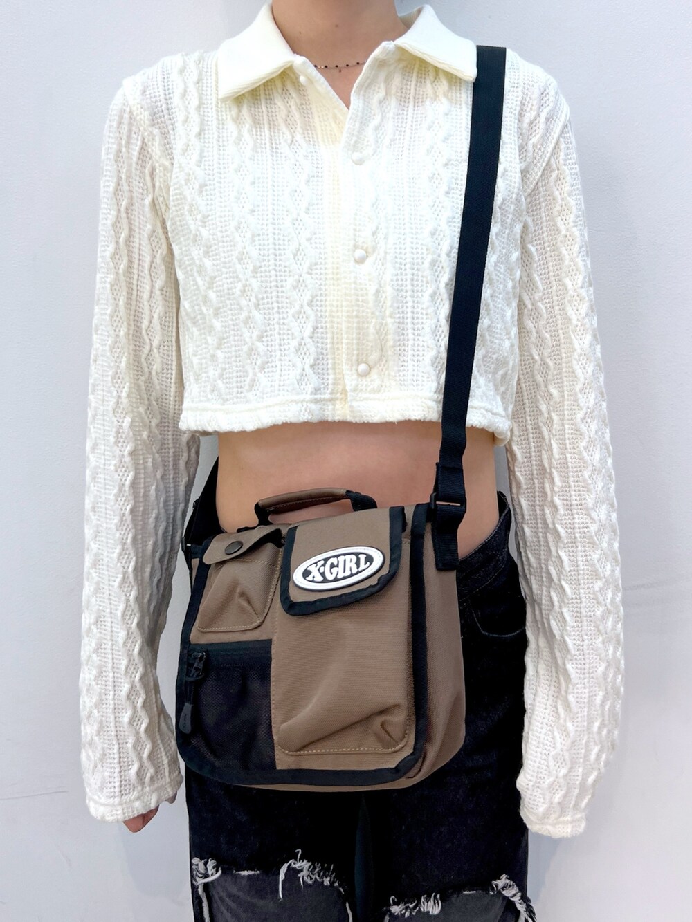 ブラック系のデニムパンツ、グリーン系のショルダーバッグ、ホワイト系のシャツ/ブラウスを着用したレディースの春コーディネートの6枚目の写真