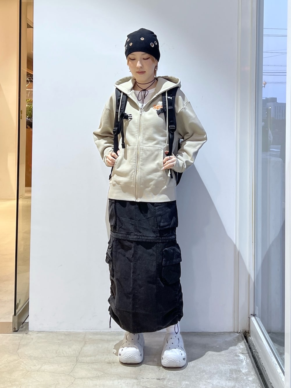 ブラック系のスカート、ブラック系のバックパック/リュック、ベージュ系のパーカーを着用したレディースの春コーディネートの2枚目の写真