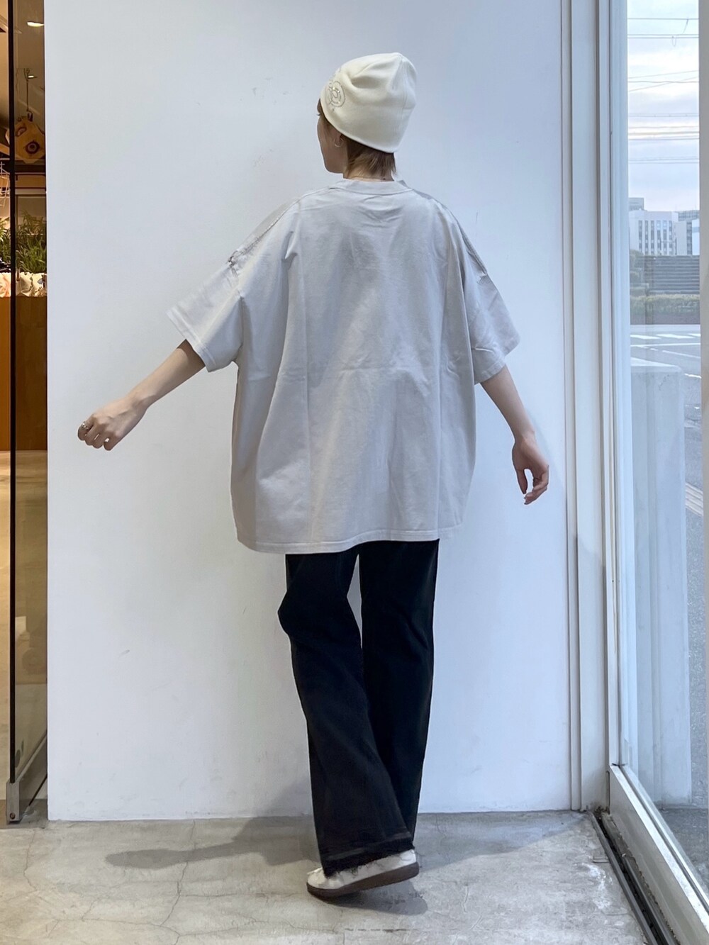 グレー系のワンピース、ブラック系のデニムパンツ、ホワイト系のニットキャップ/ビーニーを着用したレディースの春コーディネートの2枚目の写真