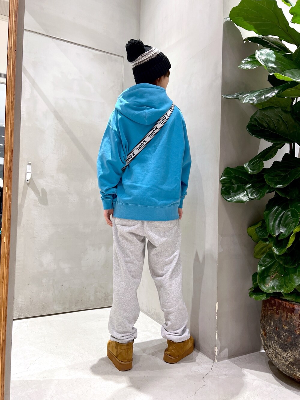 ブルー系のパーカー、ブラック系のショルダーバッグ、グレー系のスウェットパンツを着用したレディースの秋コーディネートの2枚目の写真