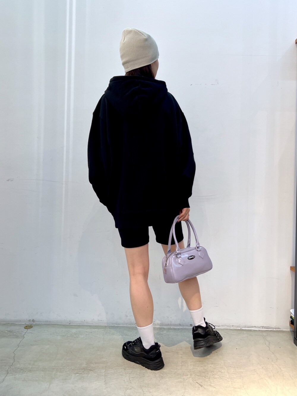 ブラック系のスウェットパンツ、パープル系のハンドバッグ、ブラック系のパーカーを着用したレディースの秋コーディネートの2枚目の写真