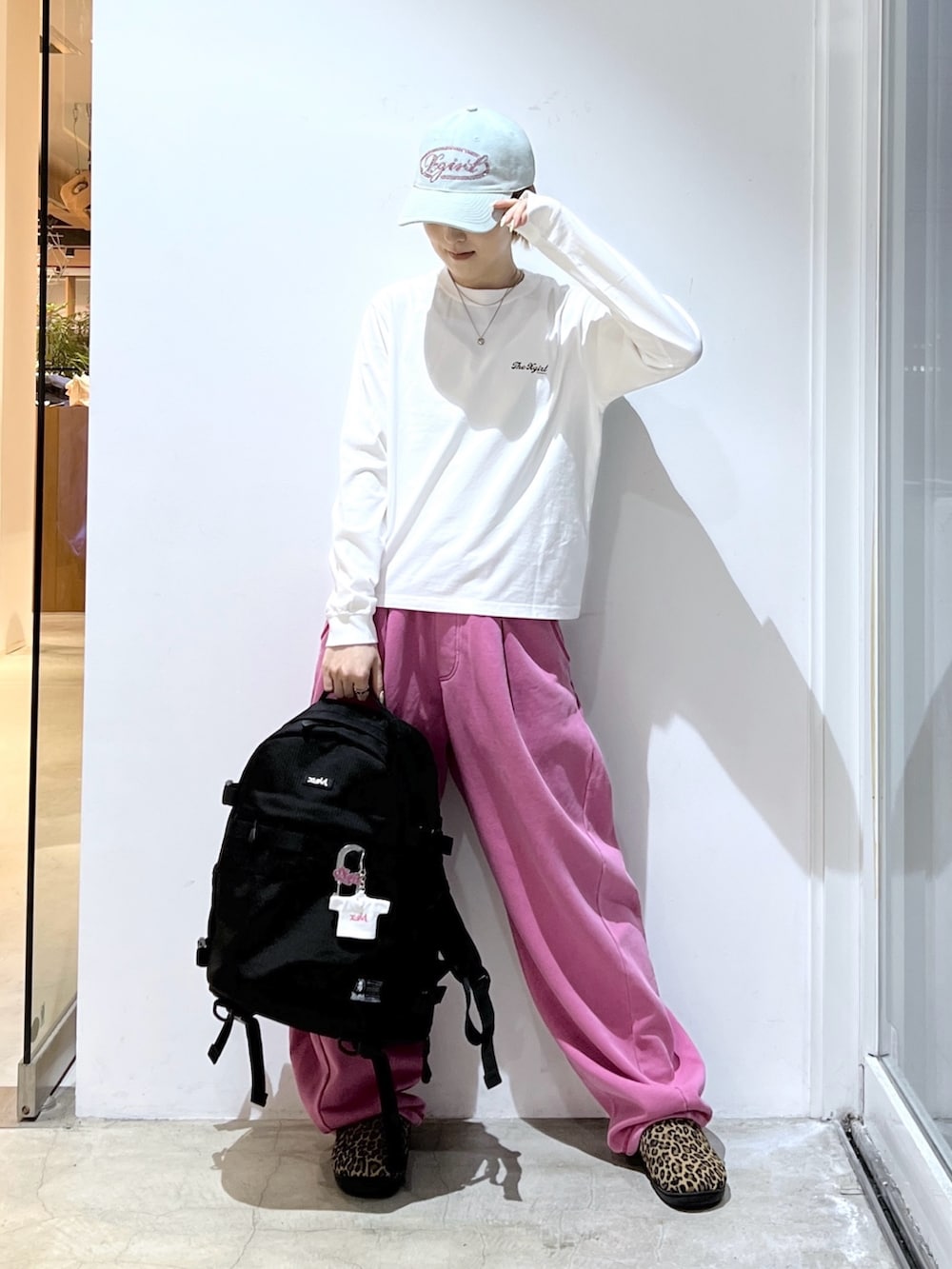 ピンク系のスウェットパンツ、ブラック系のバックパック/リュック、ホワイト系のTシャツ/カットソーを着用したレディースの春コーディネートの2枚目の写真