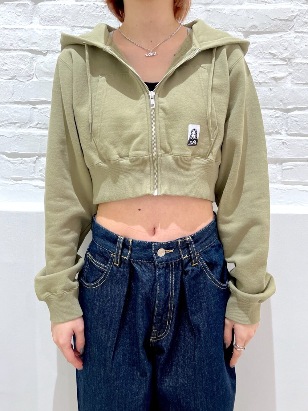 ブルー系のデニムパンツ、グリーン系のパーカー、ベージュ系のキャップを着用したレディースの春コーディネートの3枚目の写真