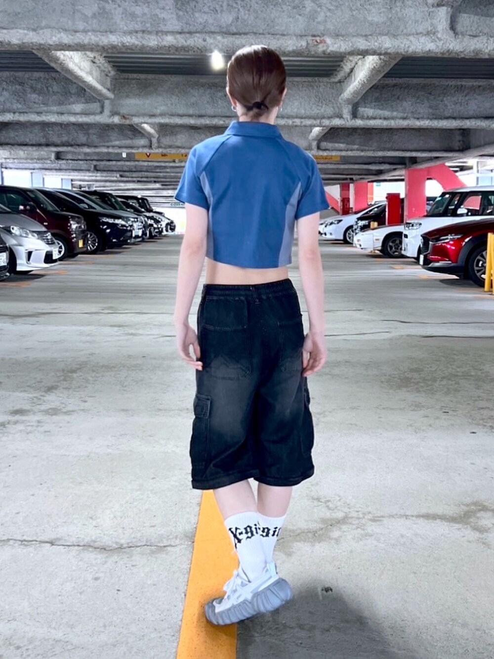 ブラック系のデニムパンツ、ブルー系のポロシャツ、ホワイト系のソックス/靴下を着用したレディースの春コーディネートの2枚目の写真