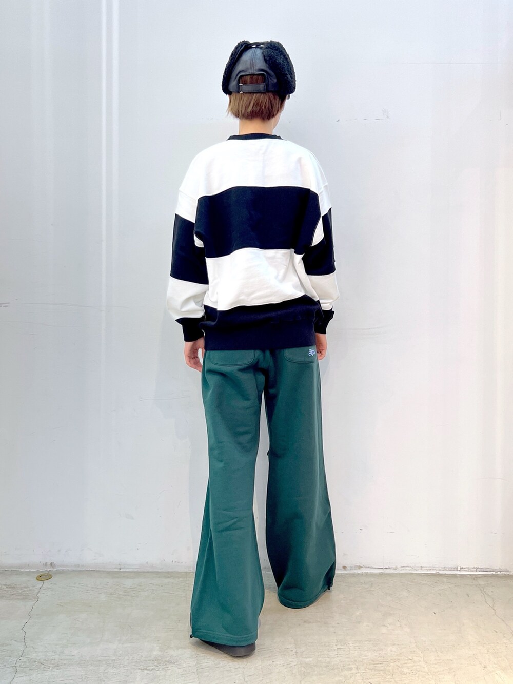 グリーン系のスウェットパンツ、ホワイト系のスウェット、ブラック系のキャップを着用したレディースの秋コーディネートの2枚目の写真