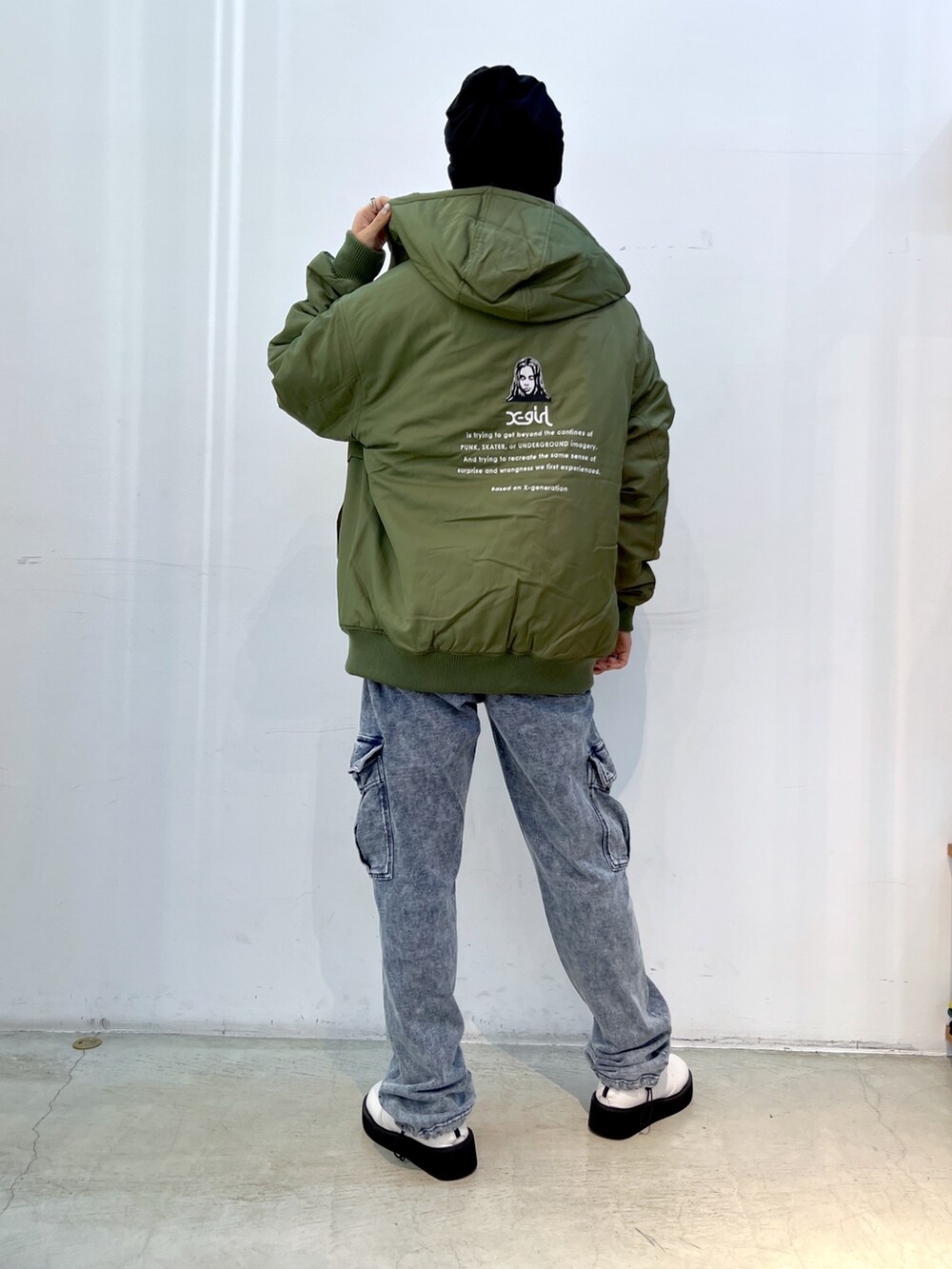 ブルー系のスウェットパンツ、グリーン系のナイロンジャケット、ホワイト系のTシャツ/カットソーを着用したレディースの秋コーディネートの2枚目の写真