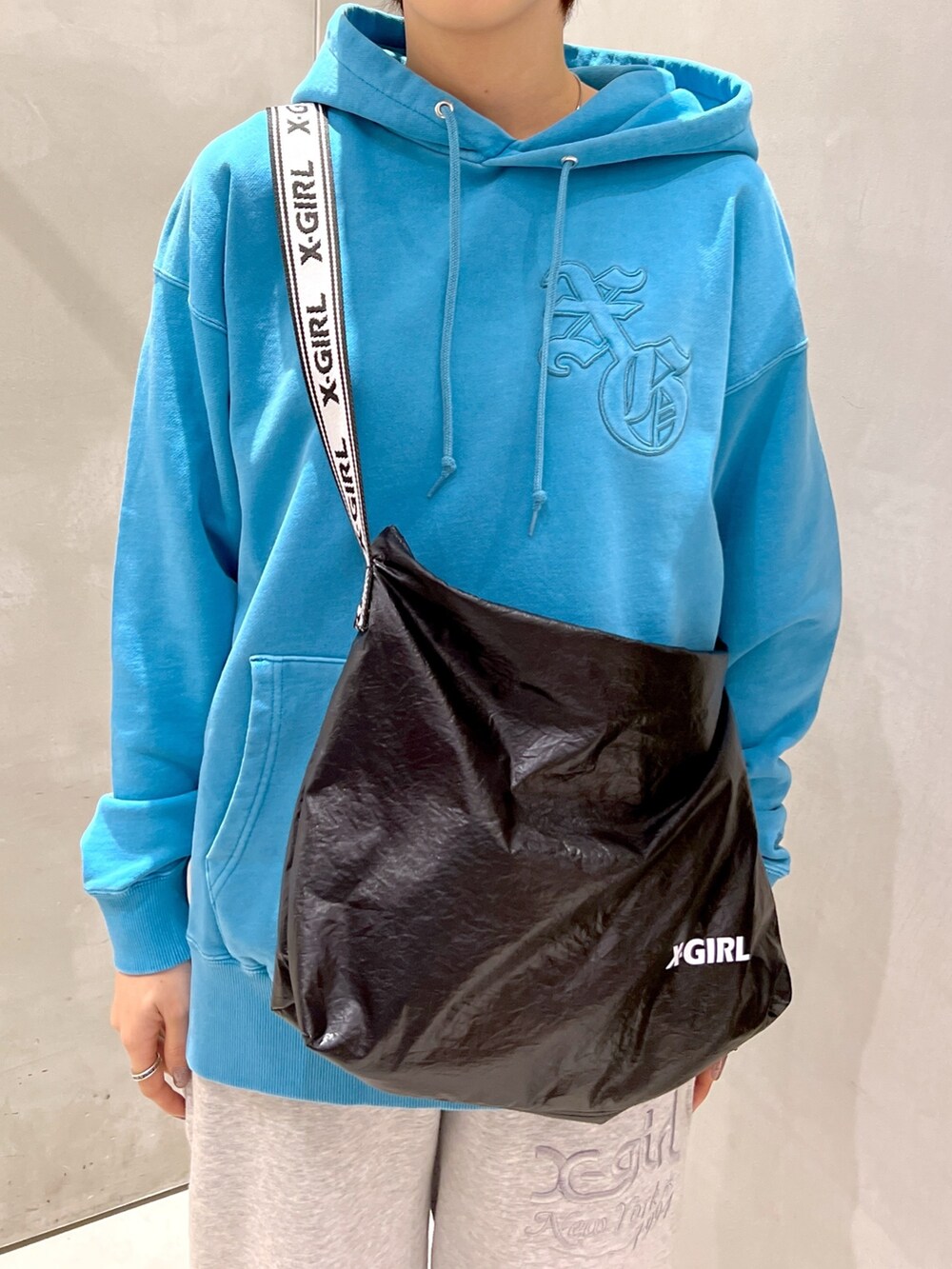 ブルー系のパーカー、ブラック系のショルダーバッグ、グレー系のスウェットパンツを着用したレディースの秋コーディネートの5枚目の写真