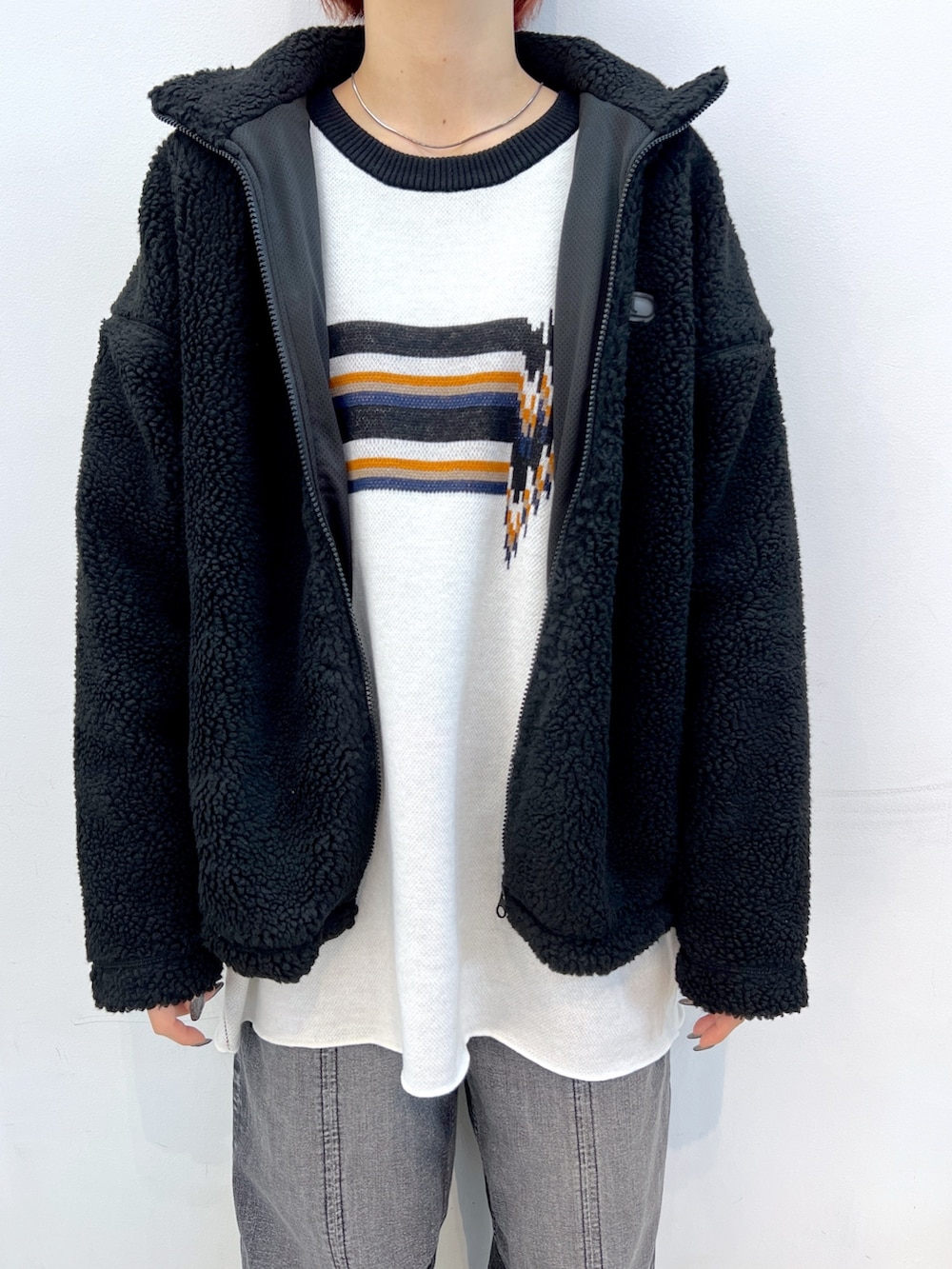 ブラック系のデニムパンツ、ホワイト系のニット/セーター、ブラック系のブルゾンを着用したレディースの冬コーディネートの5枚目の写真