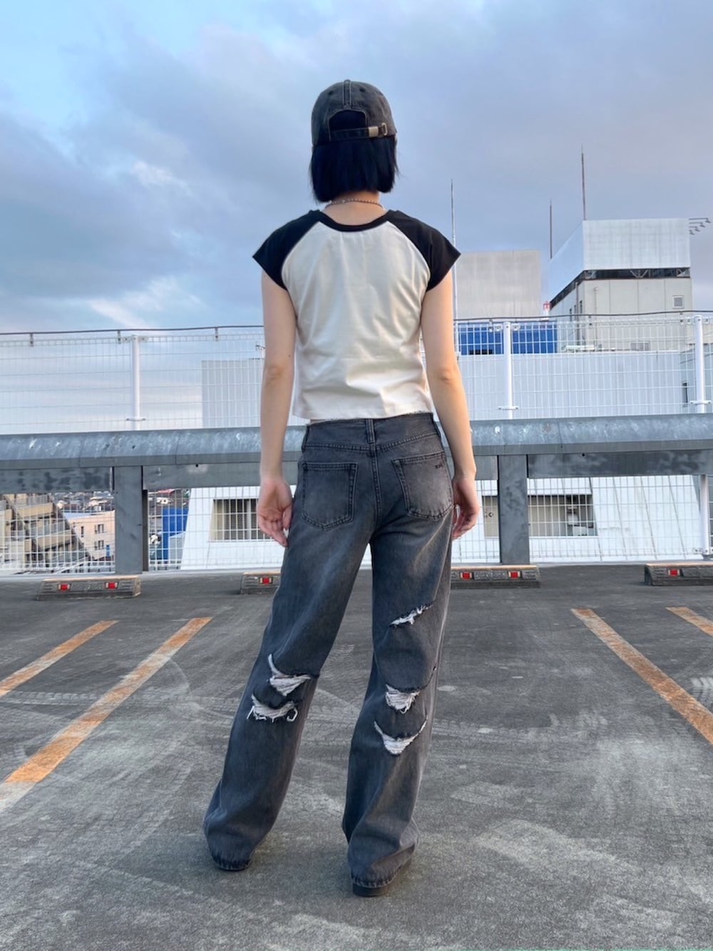 ブラック系のデニムパンツ、ホワイト系のTシャツ/カットソー、ブラック系のキャップを着用したレディースの夏コーディネートの2枚目の写真