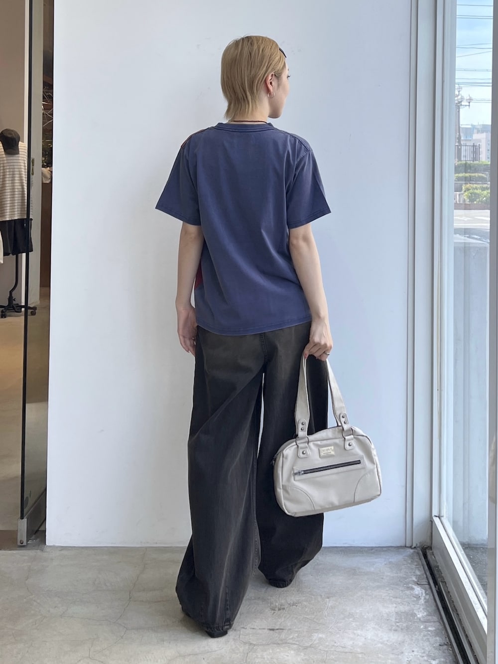 ホワイト系のハンドバッグ、ブラウン系のデニムパンツ、ブルー系のTシャツ/カットソーを着用したレディースの夏コーディネートの2枚目の写真