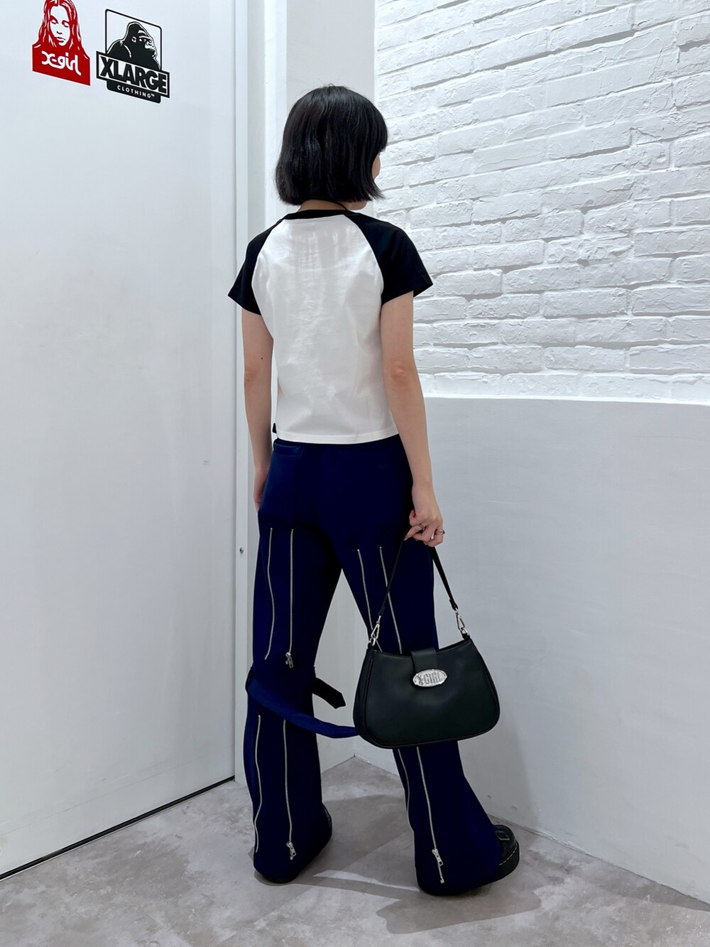 ブラック系のショルダーバッグ、ブルー系のその他パンツ、ホワイト系のTシャツ/カットソーを着用したレディースの夏コーディネートの2枚目の写真