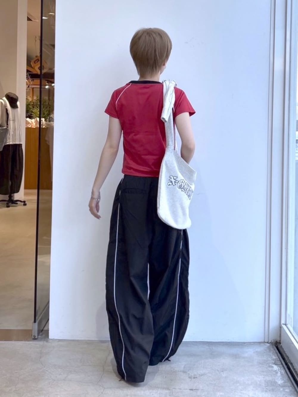 ブラック系のその他パンツ、レッド系のTシャツ/カットソー、グレー系のショルダーバッグを着用したレディースの春コーディネートの2枚目の写真
