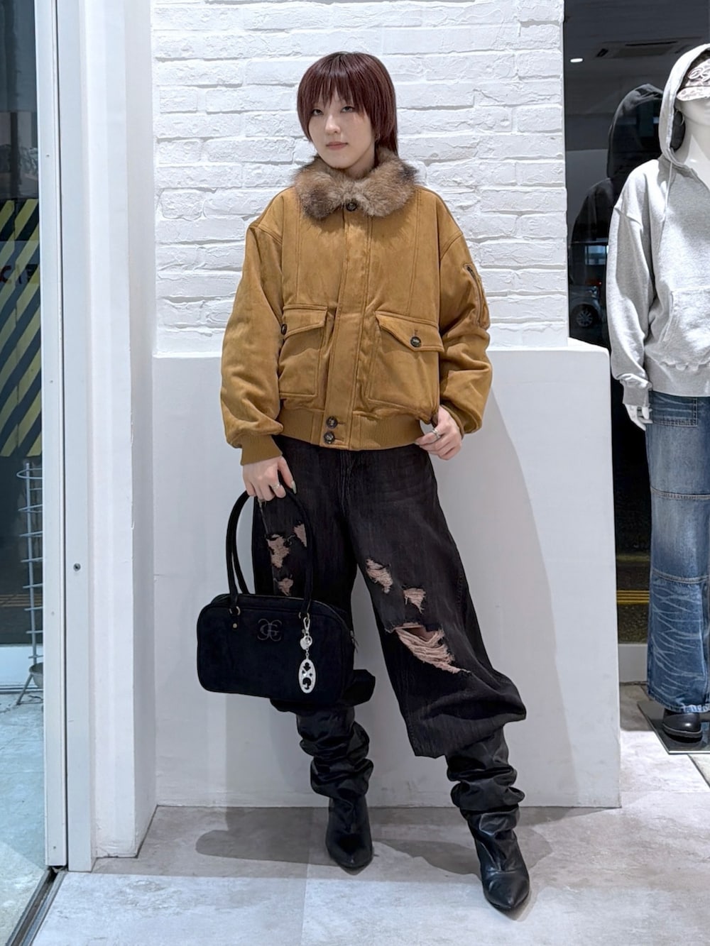 ブラック系のデニムパンツ、ブラック系のハンドバッグ、ブラウン系のブルゾンを着用したレディースの秋コーディネートの2枚目の写真