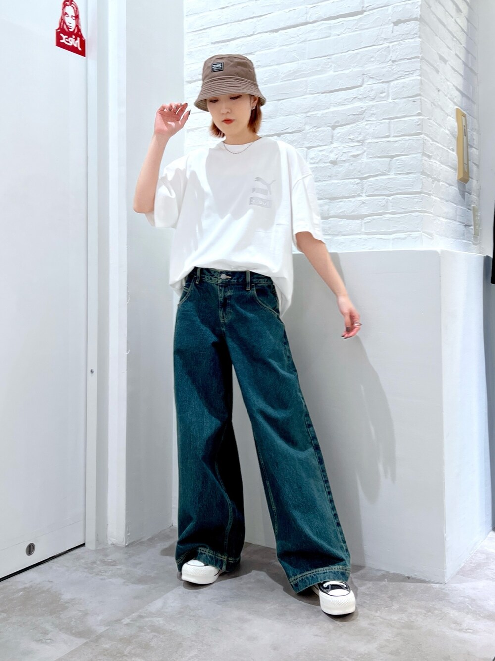 ブルー系のデニムパンツ、ホワイト系のTシャツ/カットソー、ベージュ系のハットを着用したレディースの春コーディネートの2枚目の写真