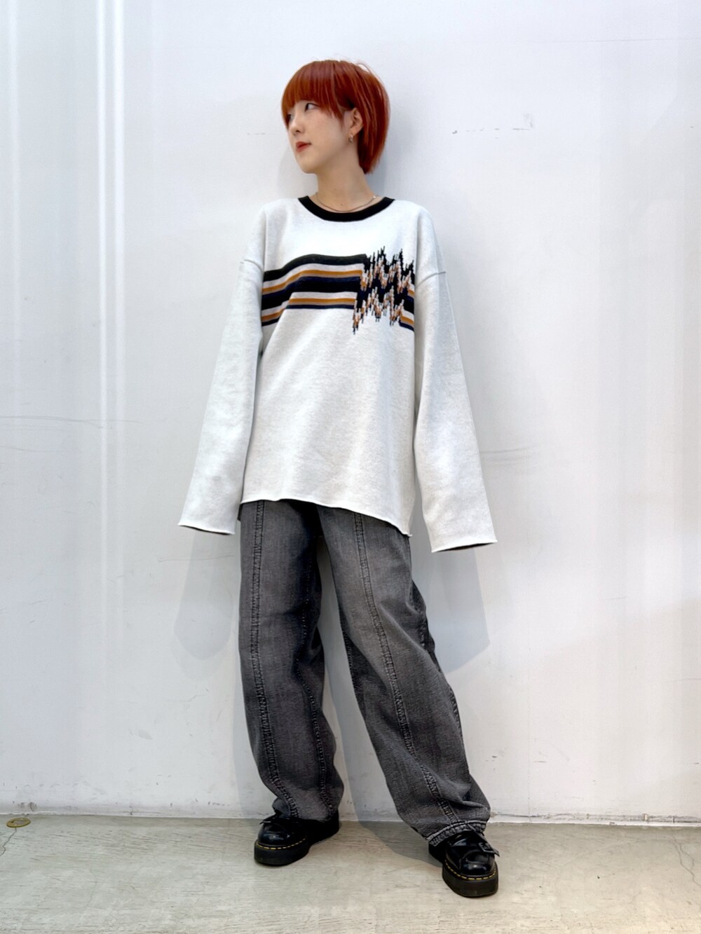 ブラック系のデニムパンツ、ホワイト系のニット/セーター、ブラック系のブルゾンを着用したレディースの冬コーディネートの3枚目の写真