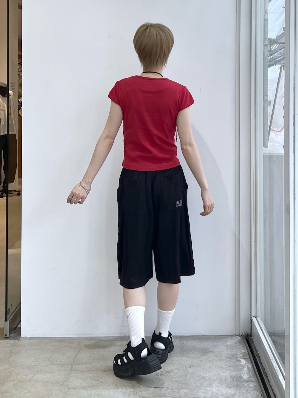 レッド系のTシャツ/カットソー、ブラック系のその他パンツ、ホワイト系のソックス/靴下を着用したレディースの春コーディネートの2枚目の写真