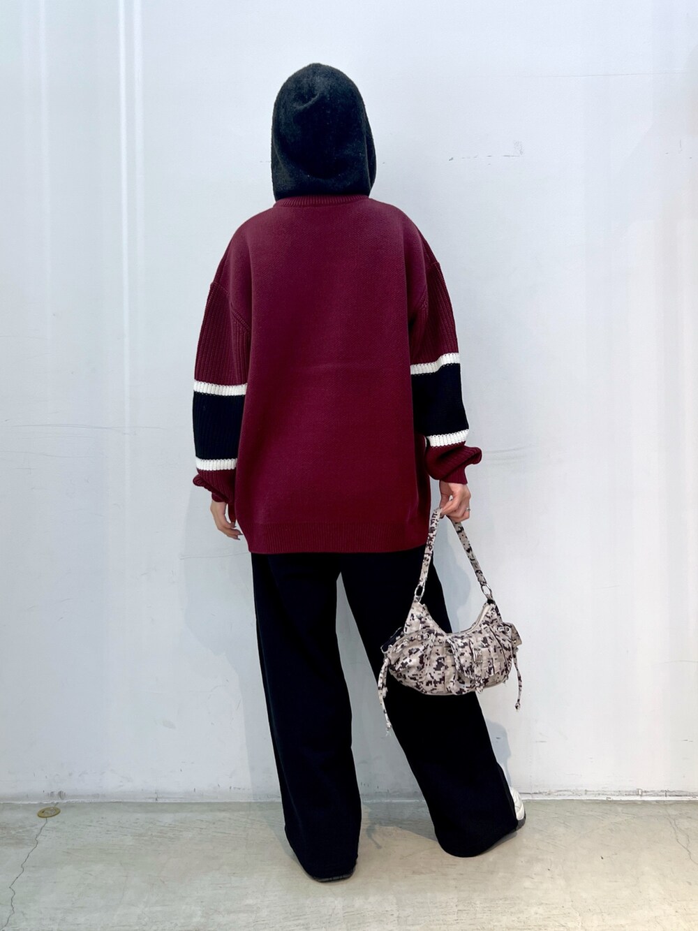 レッド系のニット/セーター、ブラック系のスウェットパンツ、ベージュ系のハンドバッグを着用したレディースの冬コーディネートの2枚目の写真