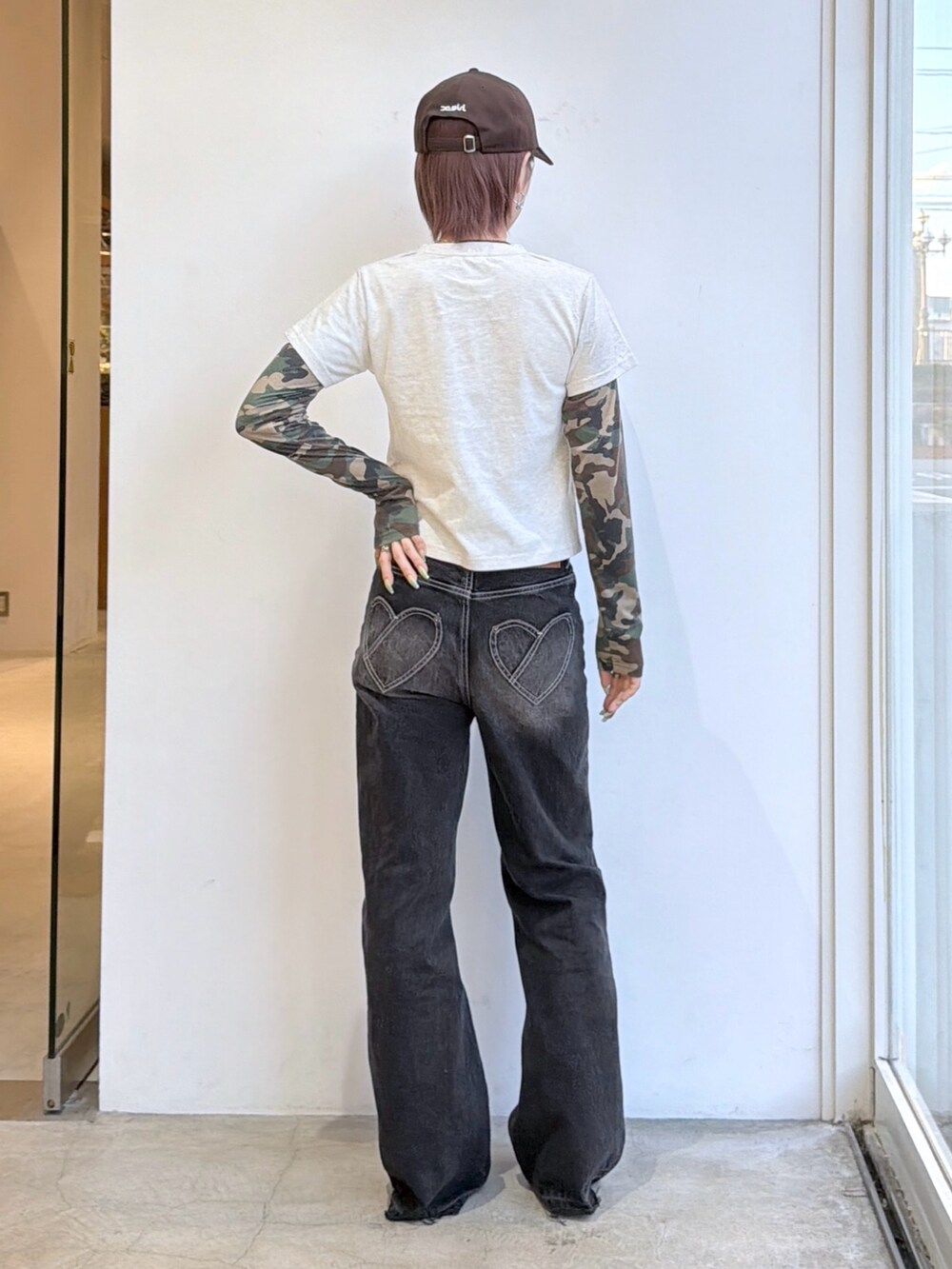 ブラック系のデニムパンツ、ホワイト系のTシャツ/カットソー、ブラウン系のキャップを着用したレディースの秋コーディネートの2枚目の写真