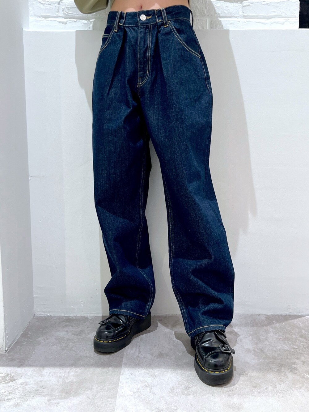 ブルー系のデニムパンツ、グリーン系のパーカー、ベージュ系のキャップを着用したレディースの春コーディネートの4枚目の写真