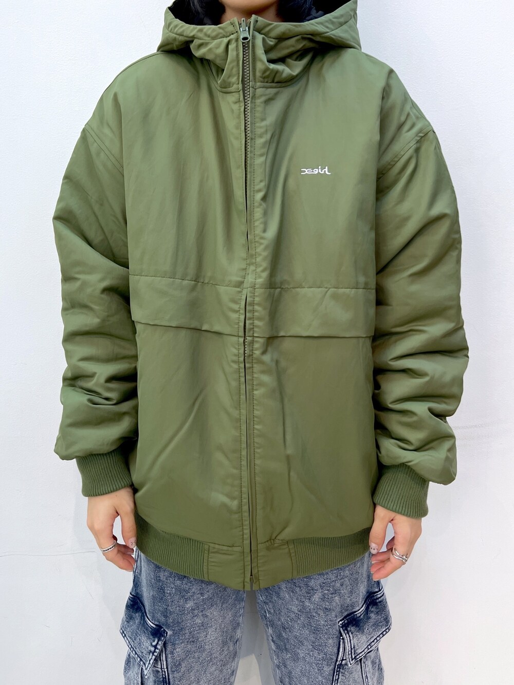 ブルー系のスウェットパンツ、グリーン系のナイロンジャケット、ホワイト系のTシャツ/カットソーを着用したレディースの秋コーディネートの5枚目の写真