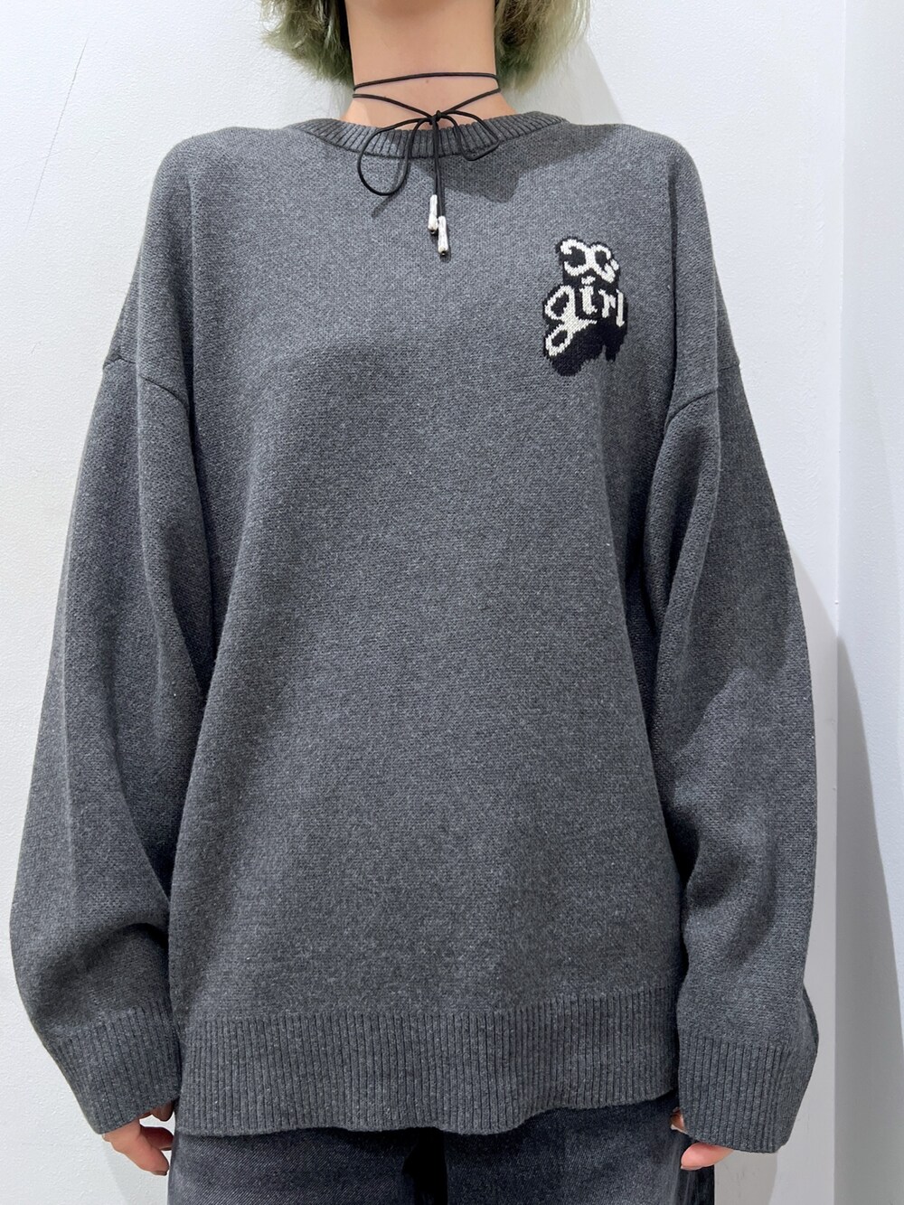 ホワイト系のショルダーバッグ、ブラック系のデニムパンツ、グレー系のニット/セーターを着用したレディースの秋コーディネートの3枚目の写真