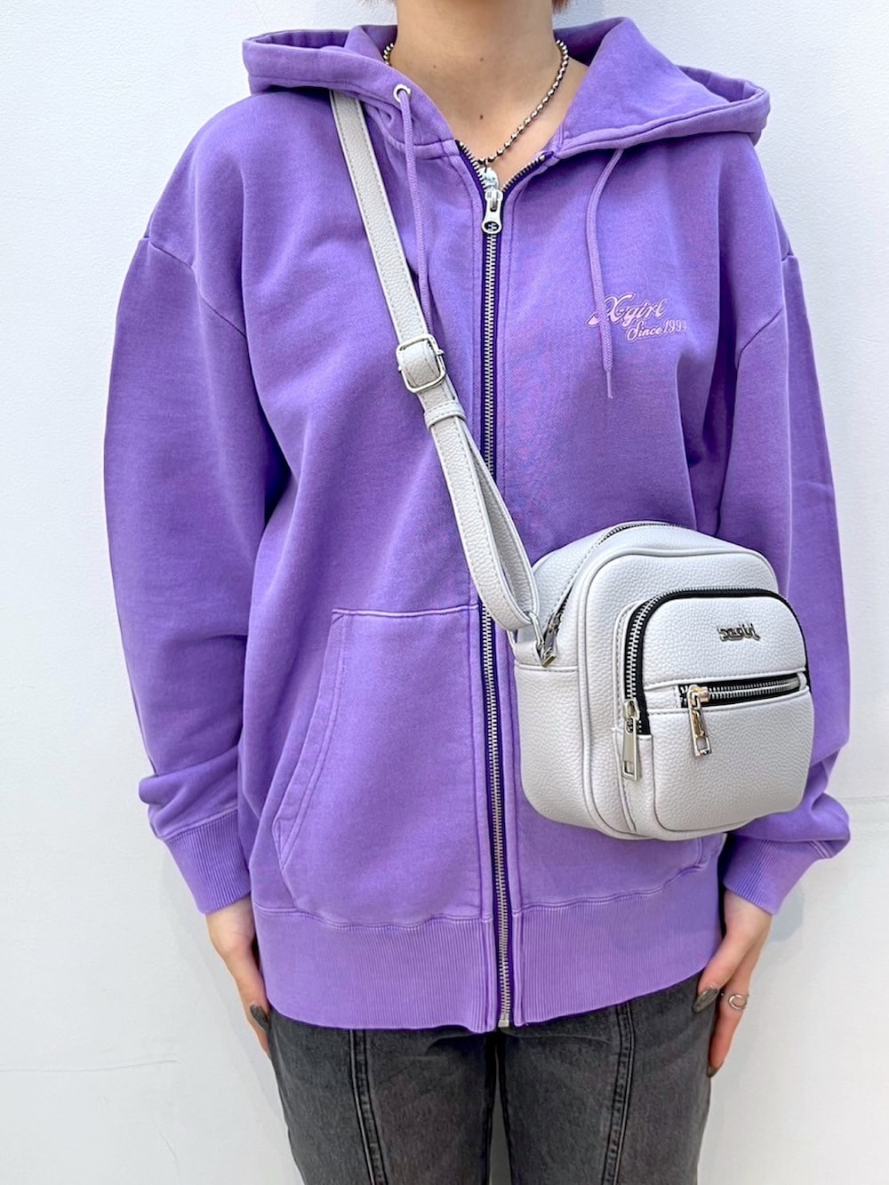 ブラック系のデニムパンツ、パープル系のパーカー、グレー系のショルダーバッグを着用したレディースの冬コーディネートの3枚目の写真