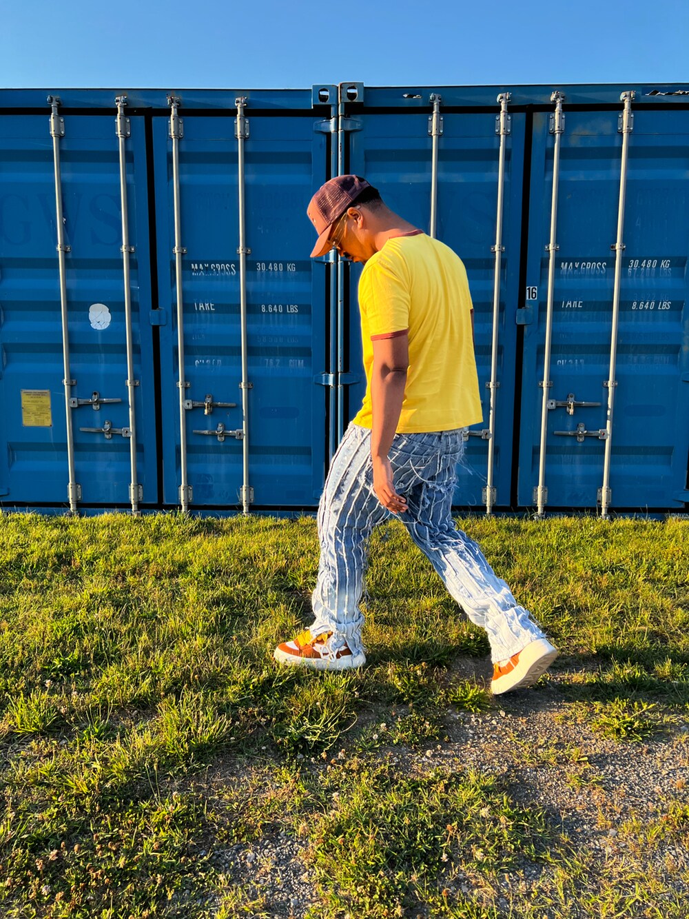 イエロー系のTシャツ/カットソー、ブルー系のデニムパンツ、ブラウン系のスニーカーを着用したメンズの夏コーディネートの2枚目の写真