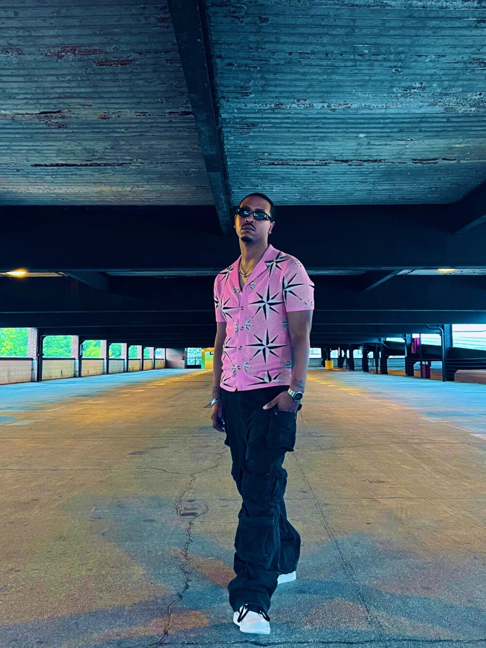 ピンク系のシャツ/ブラウス、ブラック系のカーゴパンツ、ホワイト系のスニーカーを着用したメンズの夏コーディネートの4枚目の写真