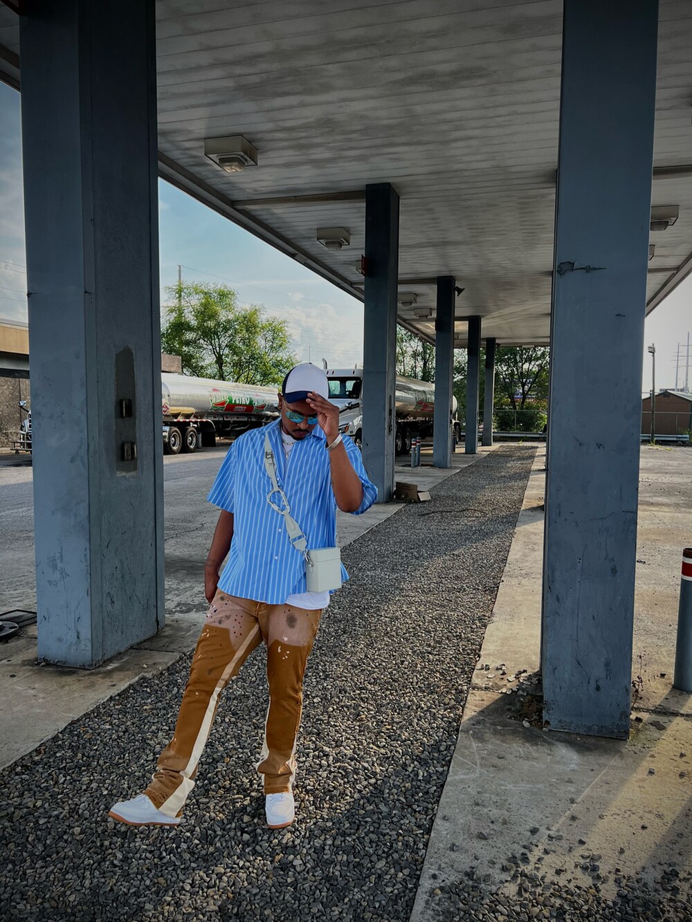 ブルー系のシャツ/ブラウス、ブラウン系のチノパンツ、ホワイト系のスニーカーを着用したメンズの夏コーディネートの2枚目の写真