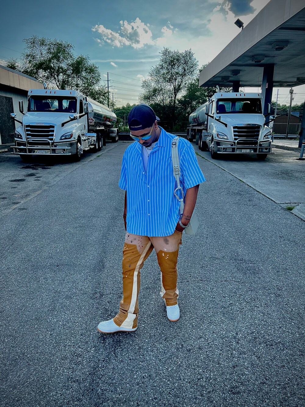 ブルー系のシャツ/ブラウス、ブラウン系のチノパンツ、ホワイト系のスニーカーを着用したメンズの夏コーディネートの4枚目の写真