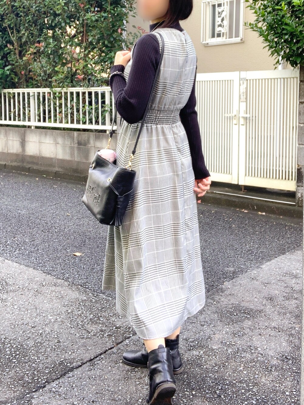 ブラック系のニット/セーター、ブラック系のショルダーバッグ、ブラック系のブーツを着用したレディースの秋コーディネートの2枚目の写真