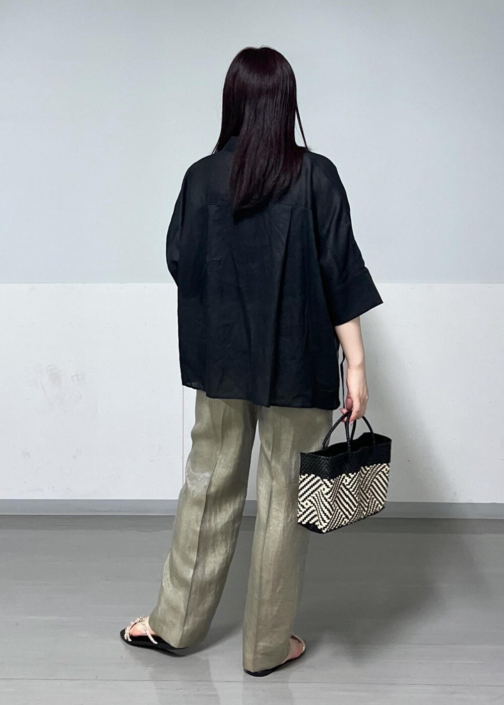 ブラック系のかごバッグ、ゴールド系のサンダル、グレー系のその他パンツを着用したレディースの春コーディネートの3枚目の写真