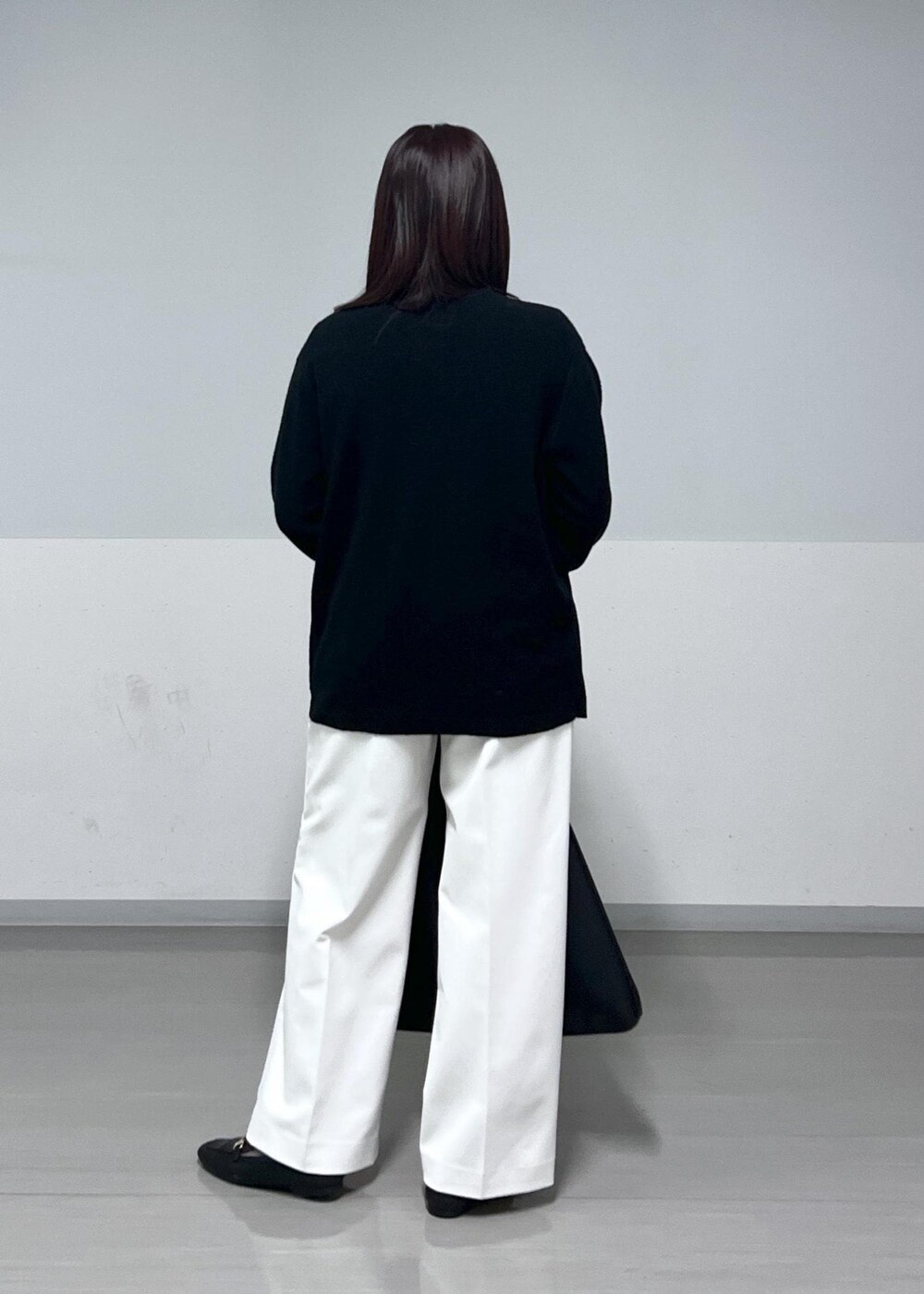 ホワイト系のその他パンツ、ブラック系のトートバッグ、ブラック系のカーディガン/ボレロを着用したレディースの冬コーディネートの3枚目の写真