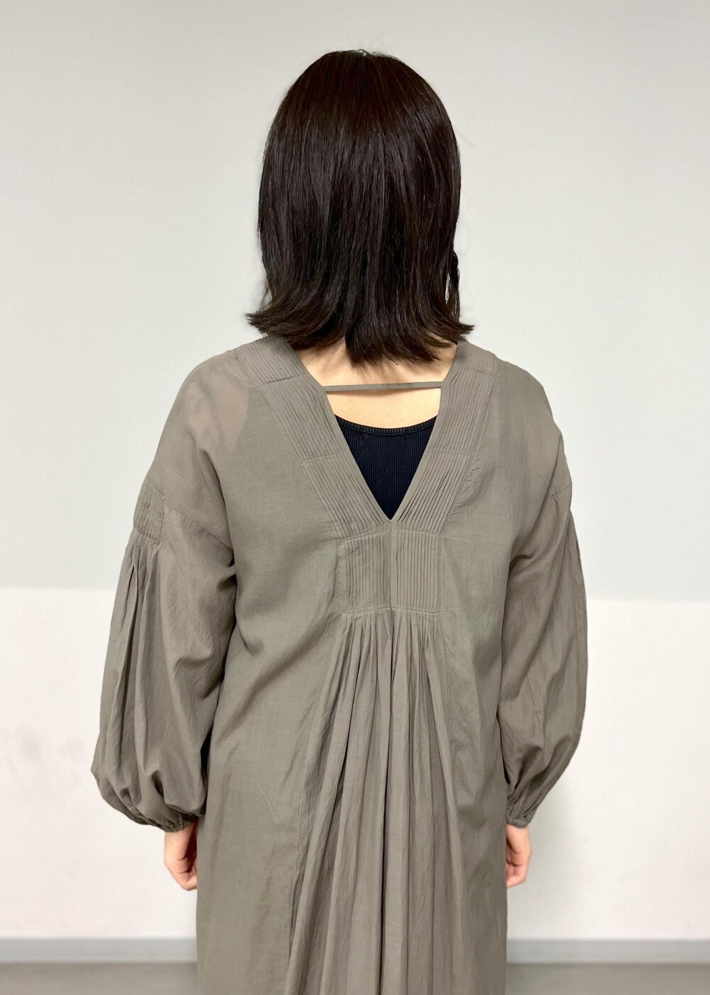 ブラック系のサンダル、グレー系のワンピース、ブラック系のかごバッグを着用したレディースの春コーディネートの6枚目の写真